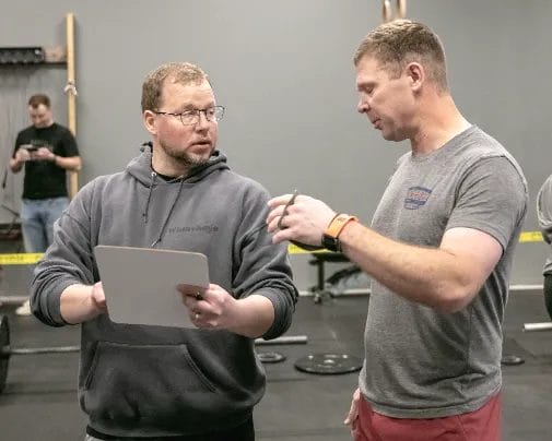 beginners talking about CrossFit workout with a coach. 